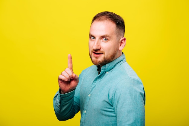 Photo wow look advertise here portrait of satisfied cute nice man with blue shirt pointing to empty place ...