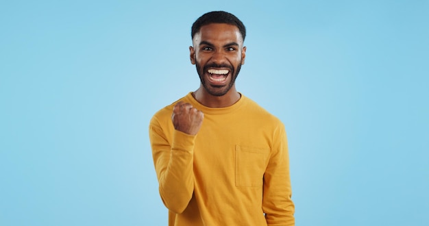 Wow news and happy man in studio with winner fist or celebration dance or victory on blue background surprise success or portrait of guy winner with energetic reaction to prize giveaway or deal