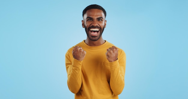 Photo wow news and happy man in studio with winner fist or celebration dance or victory on blue background surprise success or portrait of guy winner with energetic reaction to prize giveaway or deal
