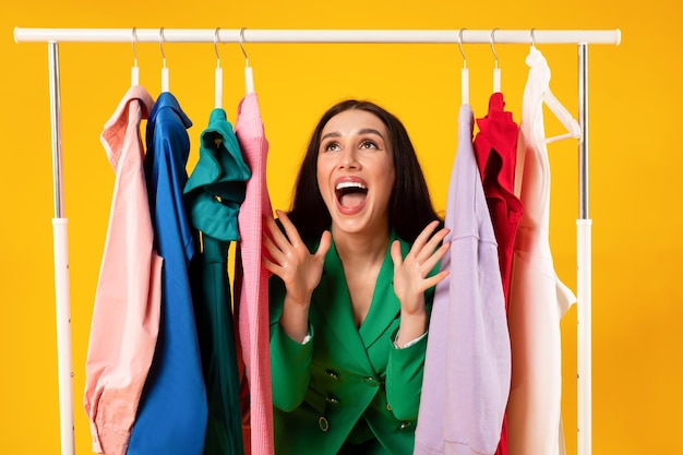 Wow sales overjoyed european stylish lady standing at clothing rail and screaming yeah with joy