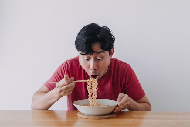 うわーとびっくりした男の変な顔がインスタントラーメンを食べる