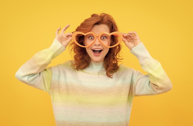 Photo wow time for fun happy girl wear glasses birthday party celebration express happiness positive emotions cheerful lady on yellow background funny redhead woman in party glasses