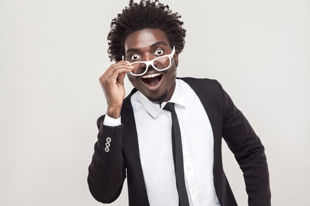 Wow! Unbeliveble news. Man in white glasses looking at camera with surprised face. Studio shot