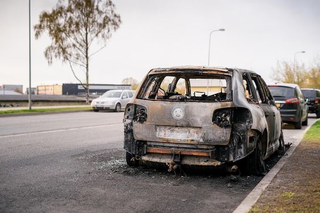 Wrak van verbrande auto aan de kant van de weg