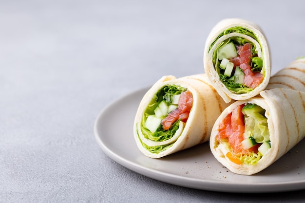 Wrap sandwich roll met vis, zalm en groenten Grijze achtergrond Kopieer ruimte Close-up