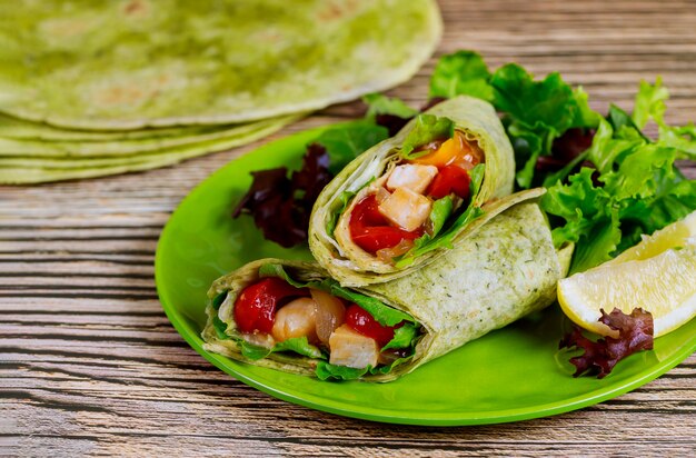 Wrap with grilled chicken and vegetable on plate with green salad and lemon