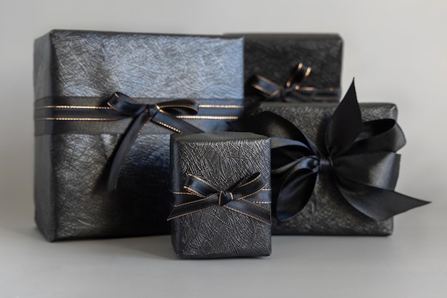 Wrapped Black Gift Boxes with a ribbon bow on grey close up