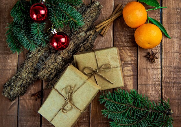 Wrapped boxes with gifts lie on a brown wooden board, and around are tangerines