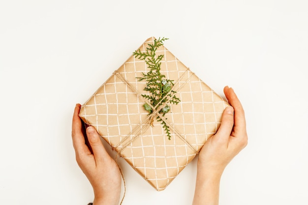 Foto regalo di natale avvolto nelle mani della donna sopra sfondo bianco