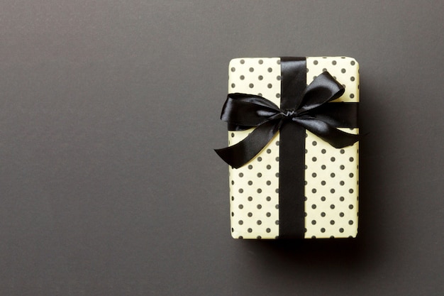 Wrapped Christmas or other holiday handmade present in paper  black ribbon on black . 