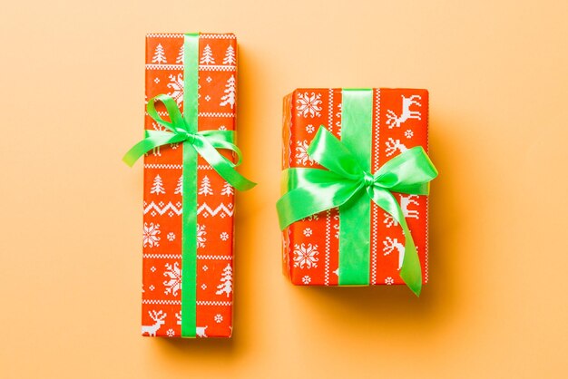 Wrapped Christmas or other holiday handmade present in paper with green ribbon on orange background Present box decoration of gift on colored table top view