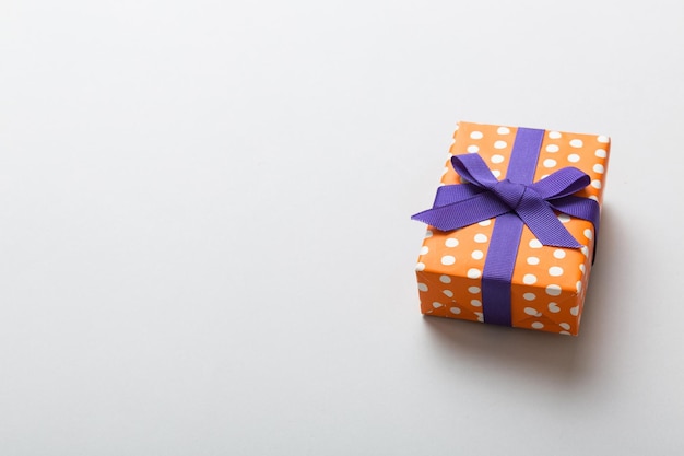 포장된 크리스마스 또는 기타 휴일 수제 선물이 색 배경에 보라색 리본이 있는 종이에 선물 상자가 복사 공간이 있는 컬러 테이블 상단 보기에 있는 선물 상자 장식