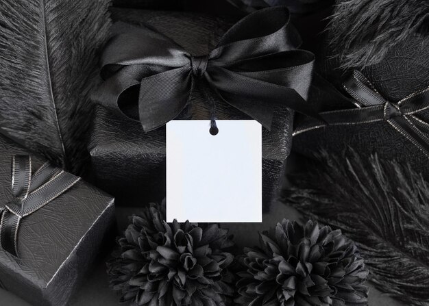 Фото Завернутые подарочные коробки с черными бумажными цветами и украшениями и макет квадратной подарочной бирки