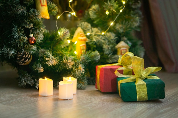 I regali incartati sono sotto l'albero. scatole in confezioni verdi e rosse legate con un nastro d'oro. concetto di regali di natale