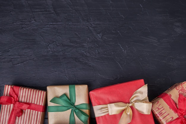 Photo wrapped gifts boxes decorated with ribbon on black  wooden . copyspace, top view