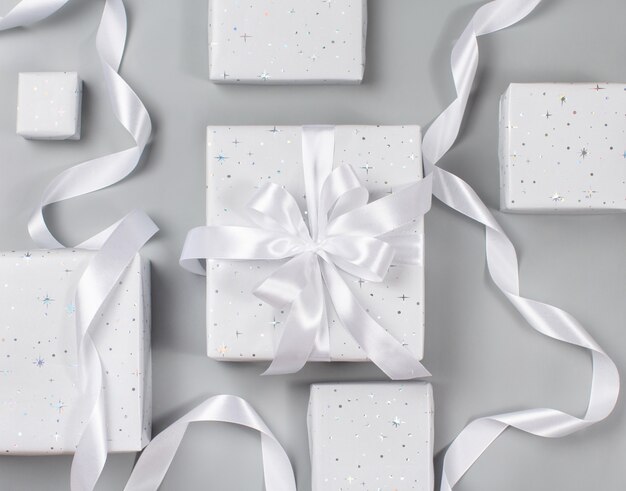 Photo wrapped grey gift boxes with white ribbon on grey top view