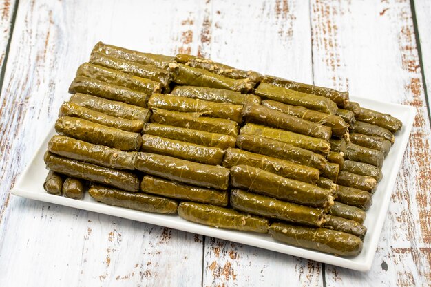 Wrapped leaves with olive oil on a wooden background Turkish and Greek cuisine the most beautiful appetizer Local name zeytinyagli yaprak sarma