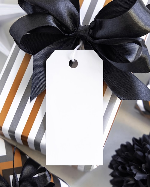 写真 縦の空白のギフトタグと黒い弓のクローズアップラベルモックアップで包まれたプレゼント