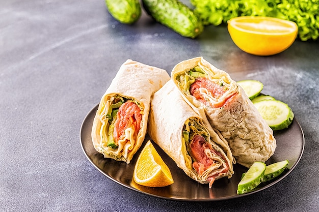 Wrapped sandwich with salmon, lettuce, cucumber and cream cheese, selective focus.