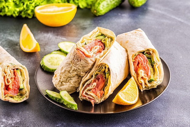 Wrapped sandwich with salmon, lettuce, cucumber and cream cheese, selective focus.