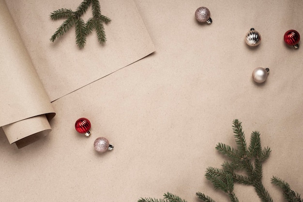 Wrapping craft paper, spruce branches, decorative balls on a craft background. Top view, flat lay.