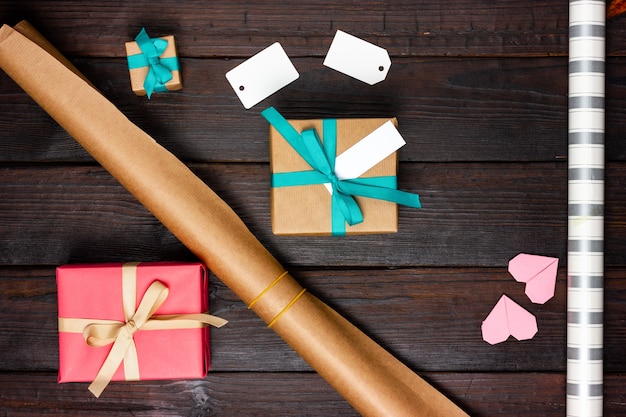 Wrapping paper, gifts and blank paper tags on a wooden table.