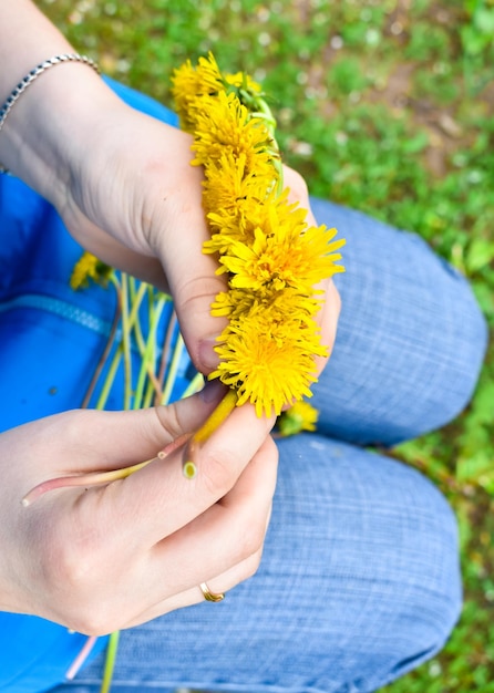 Wreath of dandelions weave female hands Yellow dandelions Flower wreath