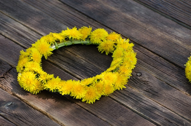 Wreath of dandelions on the wooden table, outdoors