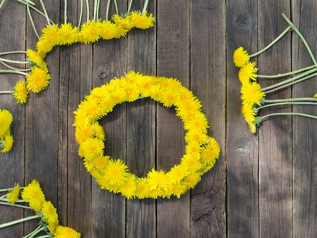 Wreath of dandelions on the wooden table