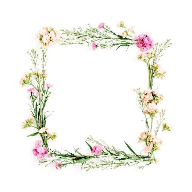 Wreath frame made of pink and beige wildflowers, green leaves, branches on white