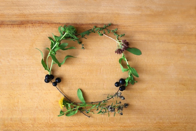 Wreath of herbs and flowers on a wooden background top view