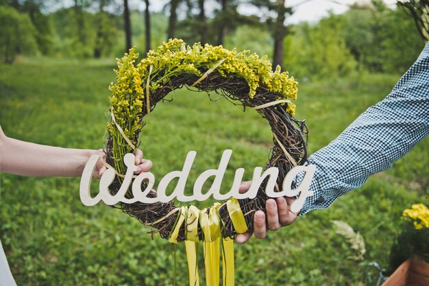 Photo wreath and inscription wedding in hands of young people