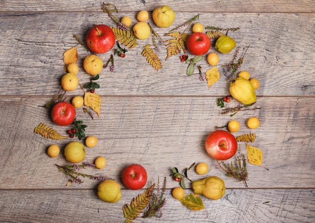 Wreath made of autumn leaves berries apples and nuts on wooden background Autumn concept