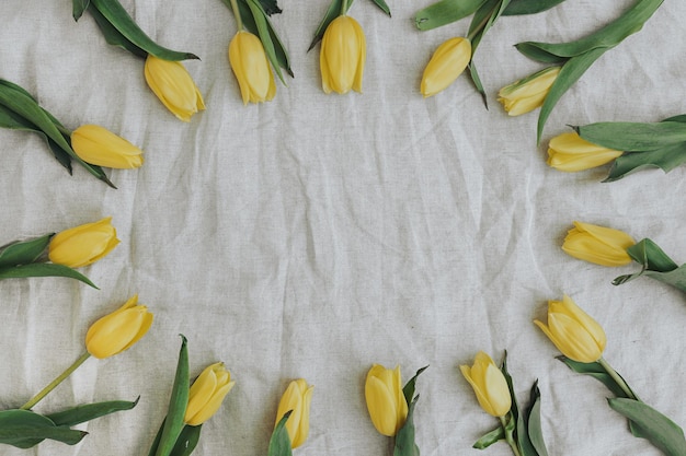 ベージュのしわくちゃのリネン布に空白のモックアップ コピー スペースを持つエレガントな黄色の花で作られた花輪フラット レイアウト トップ ビュー ブランド ブログ ウェブサイト ソーシャル メディア テンプレート