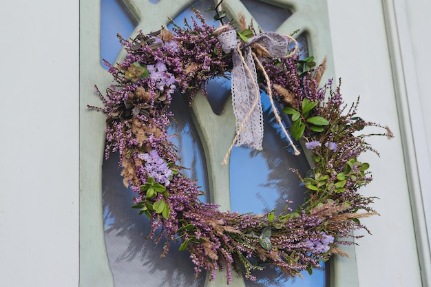 Ghirlanda di erica e altre erbe di bosco con nastro sulla porta di casa. antica tradizione celtica di celebrare l'autunno