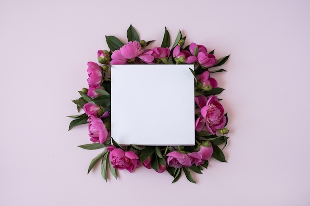 Фото Венок из элегантных розовых цветов пионов с пустым макетом копией пространства бумажный лист на пастельно-розовом фоне плоский вид сверху шаблон блога бренда в социальных сетях