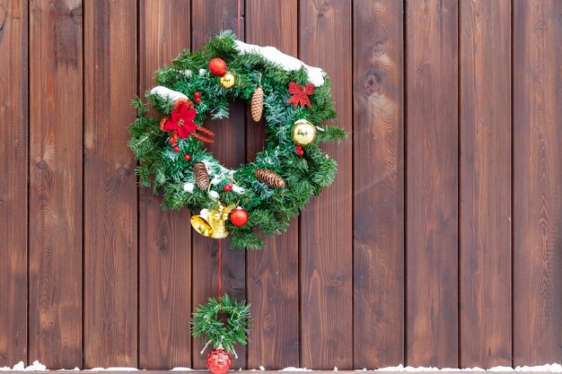 写真 垂直板の付いた茶色の木の壁にクリスマスの装飾コーンボールと雪を持つモミの枝の花輪新年とクリスマスイブ