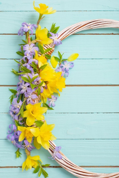 Wreath of spring flowers on blue wooden background