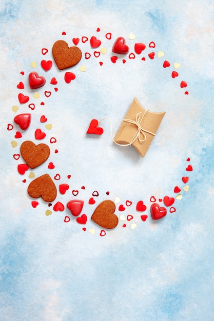 과자, 쿠키 및 파란색 배경에 선물 상자와 심장 인형의 화 환.