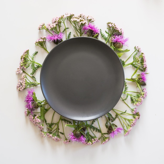 Wreath of wild purple and pink flowers on grey. Flat lay.