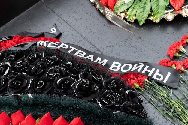 기념비에는 전쟁 희생자를 애도하는 리본이 달린 화환이 놓여 있습니다.