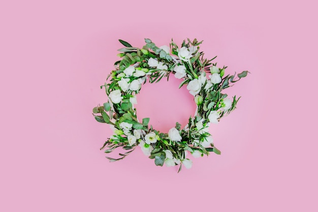 Wreath with white roses on pink background. Decorated. Above view