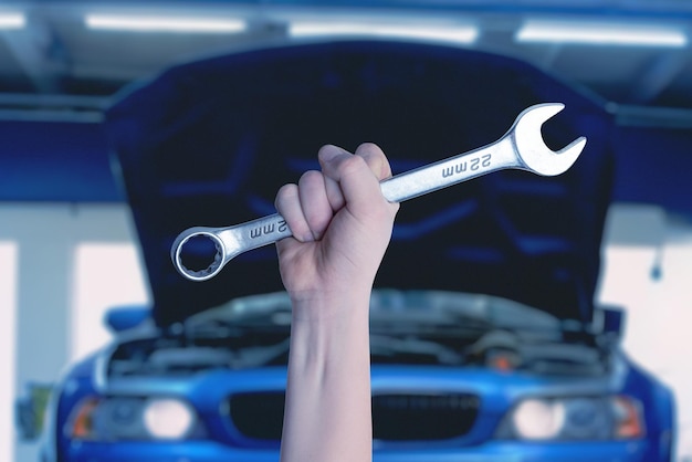 Foto chiave in mano davanti a un'auto blu con un vano motore aperto pronto per l'assistenza e la manutenzione concetto automobilistico professionale