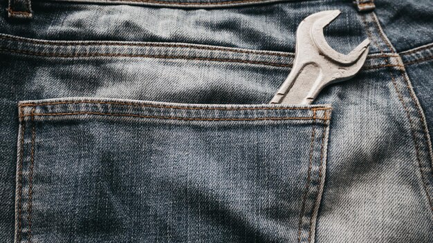 A wrench is sticking out of a pair of jeans.