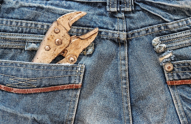 Wrench locked in a blue jeans pocket concept and background for labor days