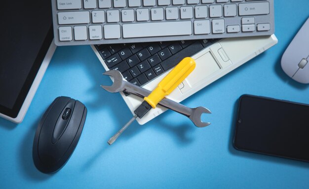 Wrench and screwdriver with a computer keyboard smartphone tablet mouse IT Service Support