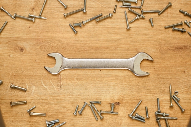 Photo wrench and screws on a wooden table.