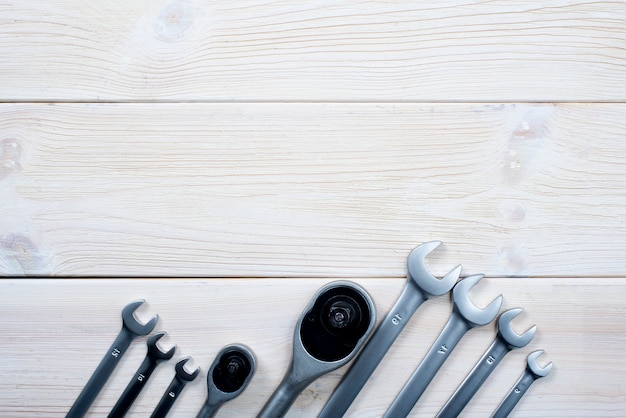 Wrenches of different sizes on a textural white wooden background. 