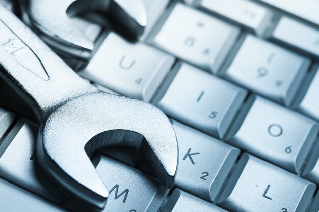 Wrenches laying on laptop keyboard, close-up