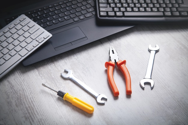 Wrenches, pliers and screwdriver with laptop and computer keyboard. IT Service. Support